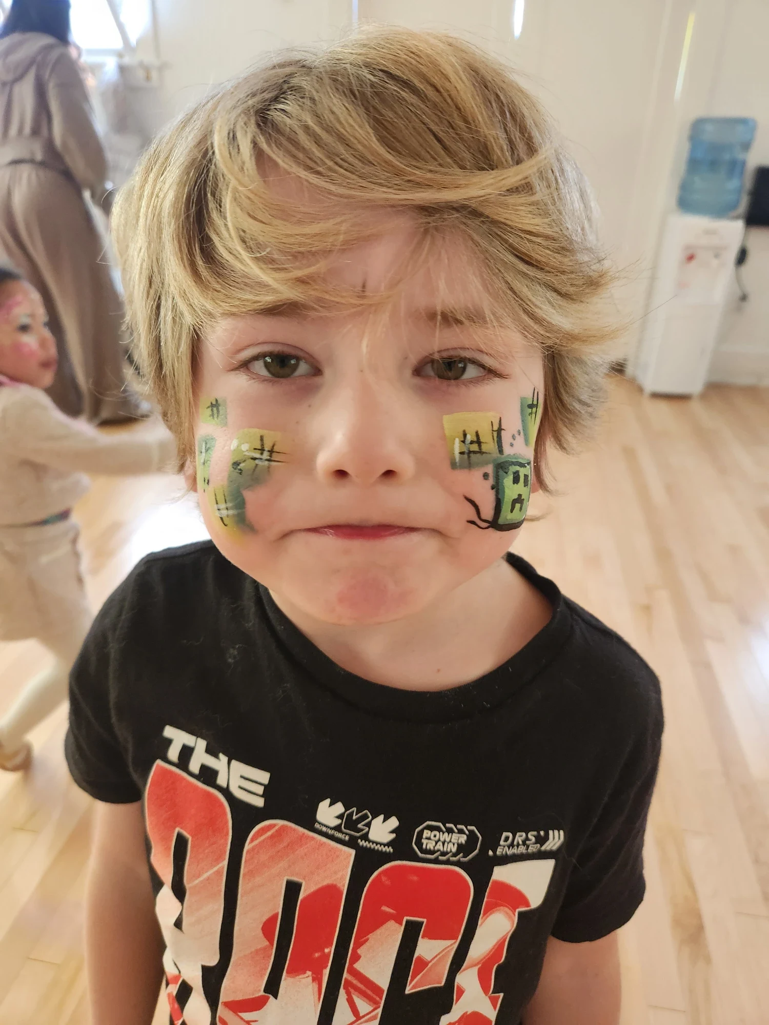Young boy with a green Minecraft-style creeper face painting