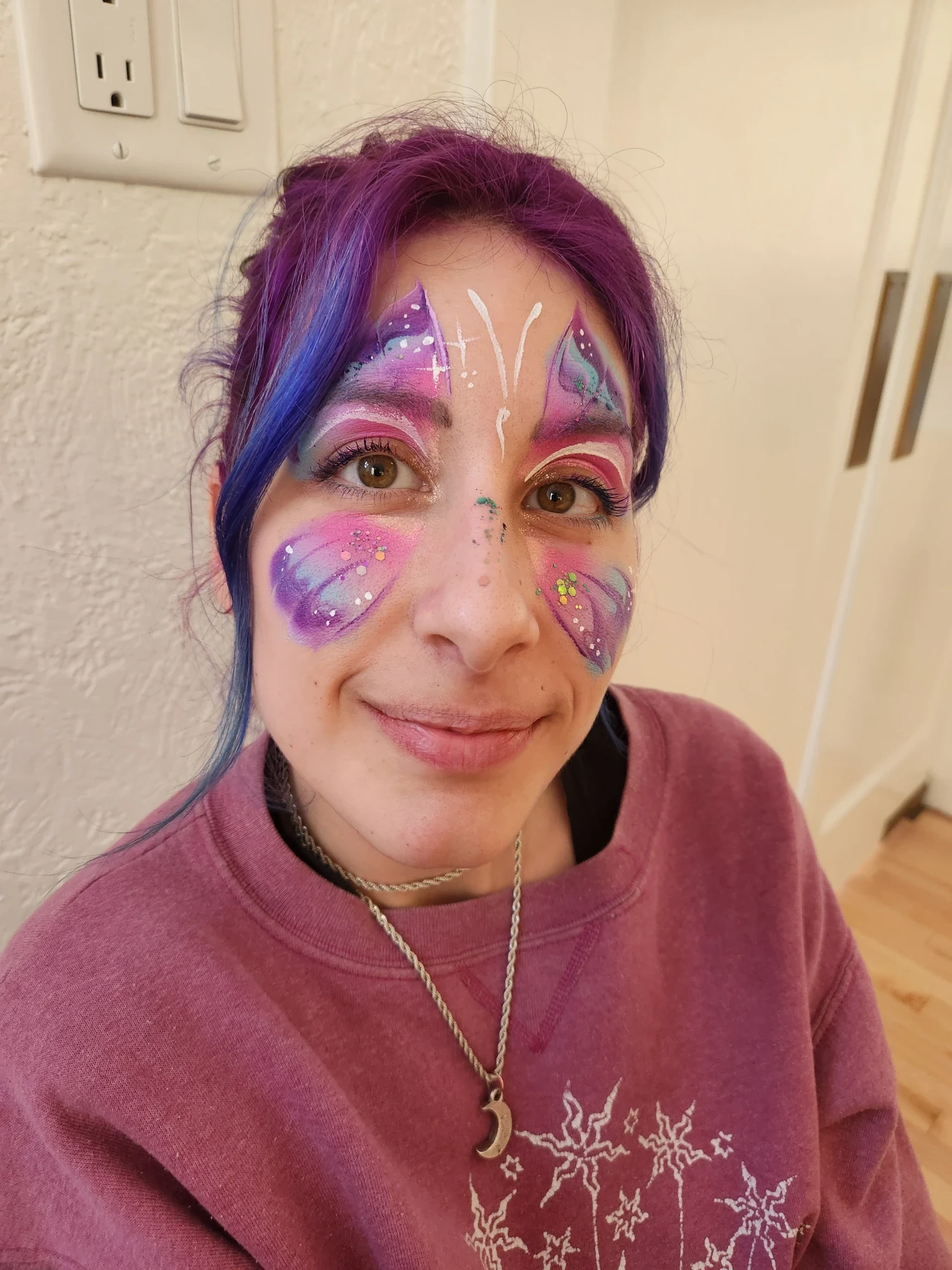 Teen with a purple and pink galaxy butterfly face painting and glitter