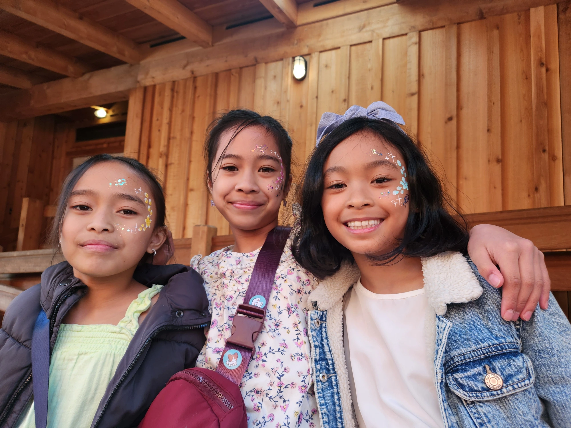 Three girls with delicate flower and glitter face painting designs