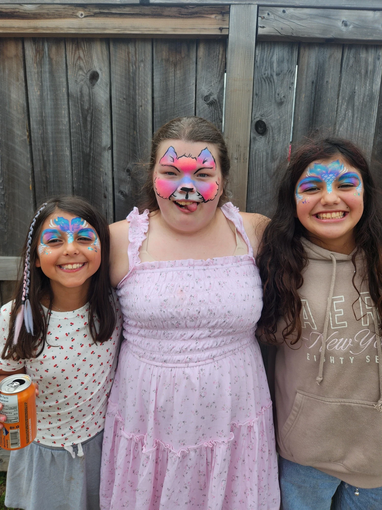 Three girls with cat and butterfly face painting designs outdoors